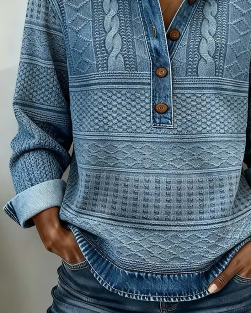 Close-up of the blue sweater's three wooden buttons, cable knit panels and curved denim-look hem 2