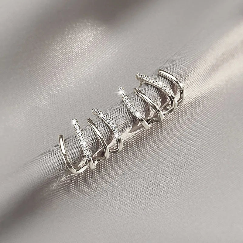 Silver-coloured version of the earrings lying on grey satin, bands alternating between plain and stone-set 6