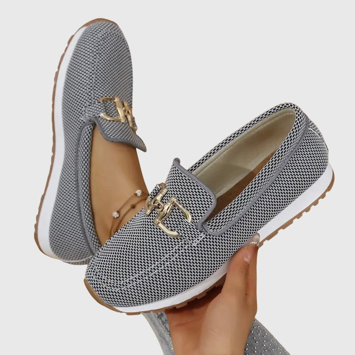 Grey mesh loafers held in a hand, showing the cushioned insole and gold buckle 8
