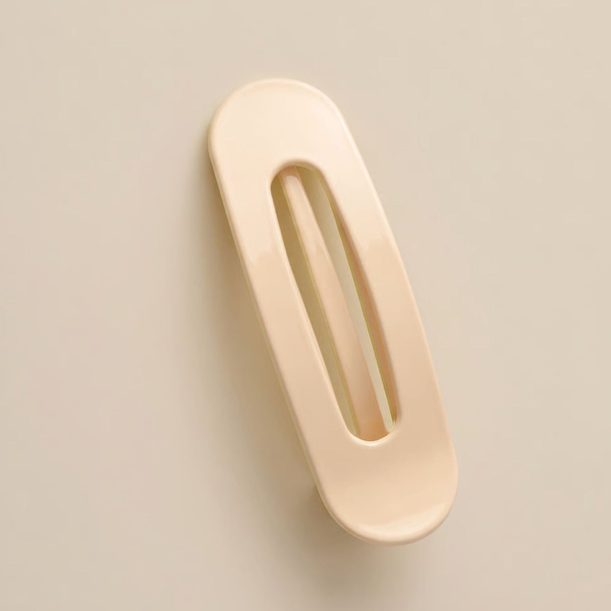 Glossy cream-peach flat clip with a long oval cut-out, shown from above on a neutral background 7
