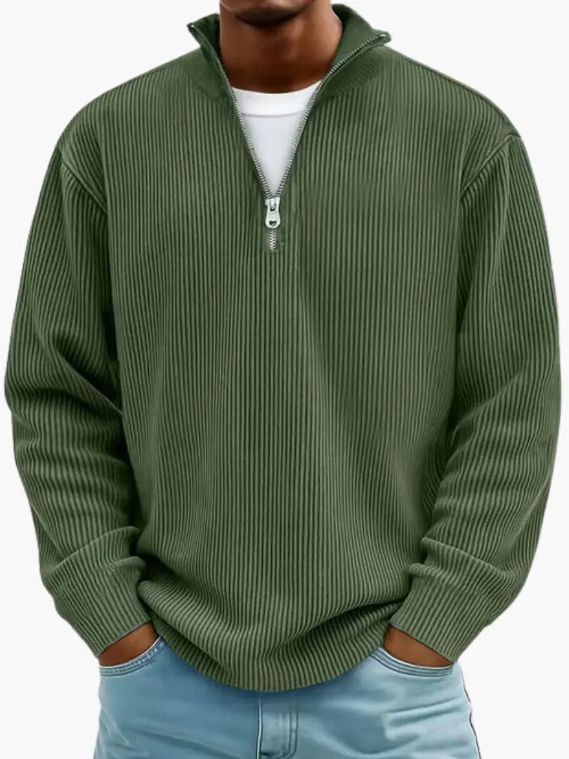 Man wearing the ribbed quarter-zip jumper in dark olive green over a white tee, hands in his light blue jeans pockets. 8