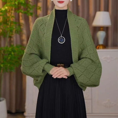 Model wearing the open knit shawl cardigan in olive green over a black top and pleated skirt 6