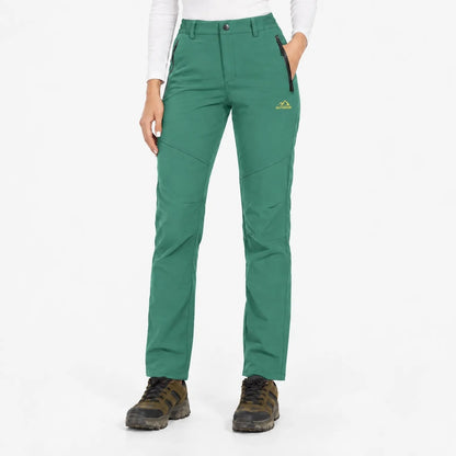 Front view of the trousers in a mid green, worn with a white long-sleeved top 13