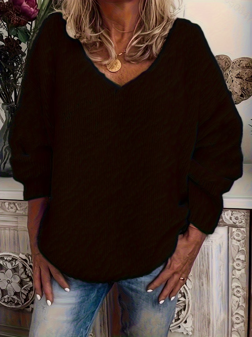 Woman wearing the chunky knit V-neck jumper in black, front view, loose sleeves and ribbed cuffs, paired with jeans. 3