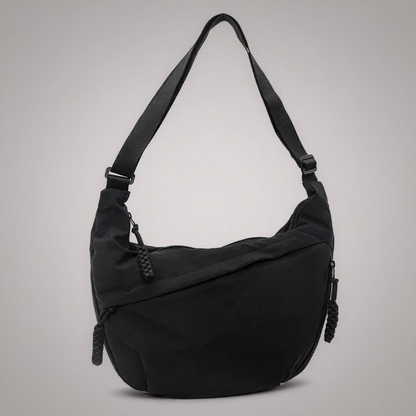 Black soft nylon-look hobo shoulder bag with adjustable strap and braided zip pulls, shown against a plain grey studio backdrop. 1