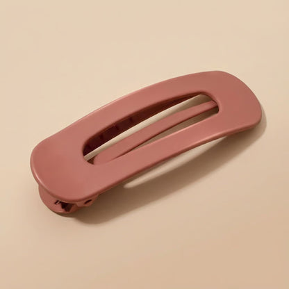 Matte dusty terracotta-pink clip at an angle, showing the oval opening and the spring hinge 9