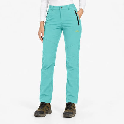 Front view of the trousers in bright turquoise, worn with hiking boots 19