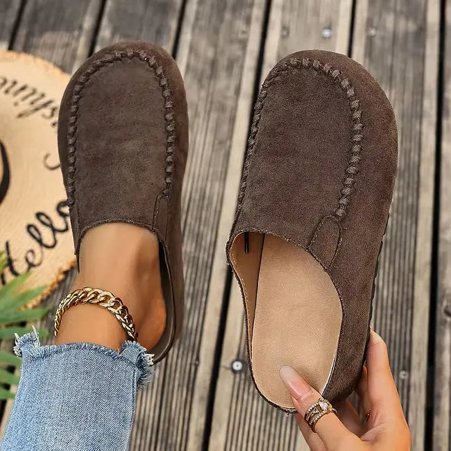 Dark brown version from above, one slip-on worn with frayed jeans and the other held open to show the tan footbed. 3