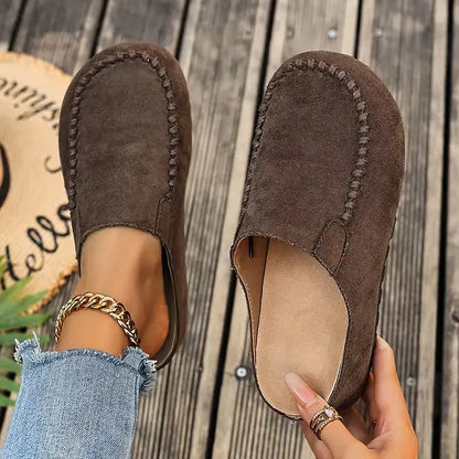 Dark brown version from above, one slip-on worn with frayed jeans and the other held open to show the tan footbed. 3