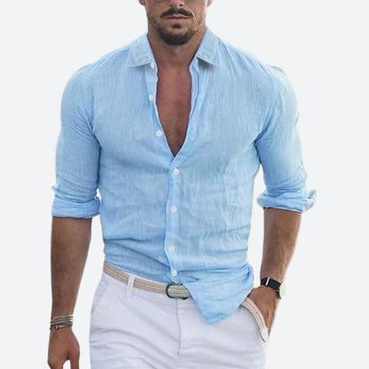 Man wearing the shirt in light sky blue, open at the collar with sleeves rolled, styled with white trousers and a woven belt. 4