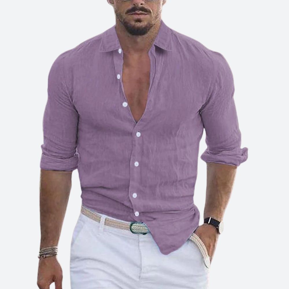 Man wearing the shirt in soft lilac purple, open at the collar with sleeves rolled, styled with white trousers and a woven belt. 9
