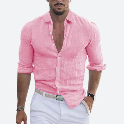 Man wearing the shirt in bright pink, open at the collar with sleeves rolled, styled with white trousers and a woven belt. 7