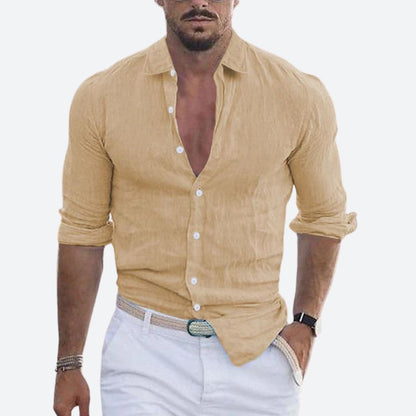 Man wearing the shirt in sandy beige, open at the collar with sleeves rolled, styled with white trousers and a woven belt. 8