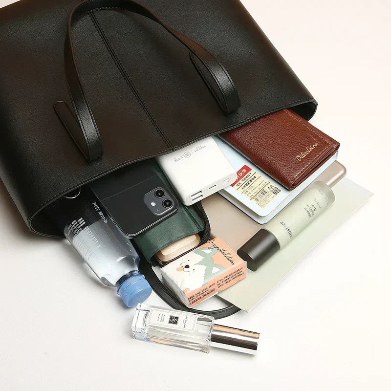 Black tote lying on its side with a phone, wallet, notebook, bottle and cosmetics spilling out 6