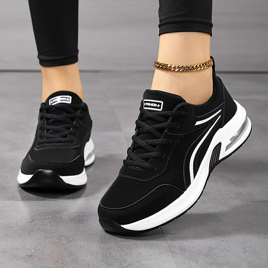 Front three-quarter view of black trainers with white side stripes, worn with black leggings and a gold anklet 2