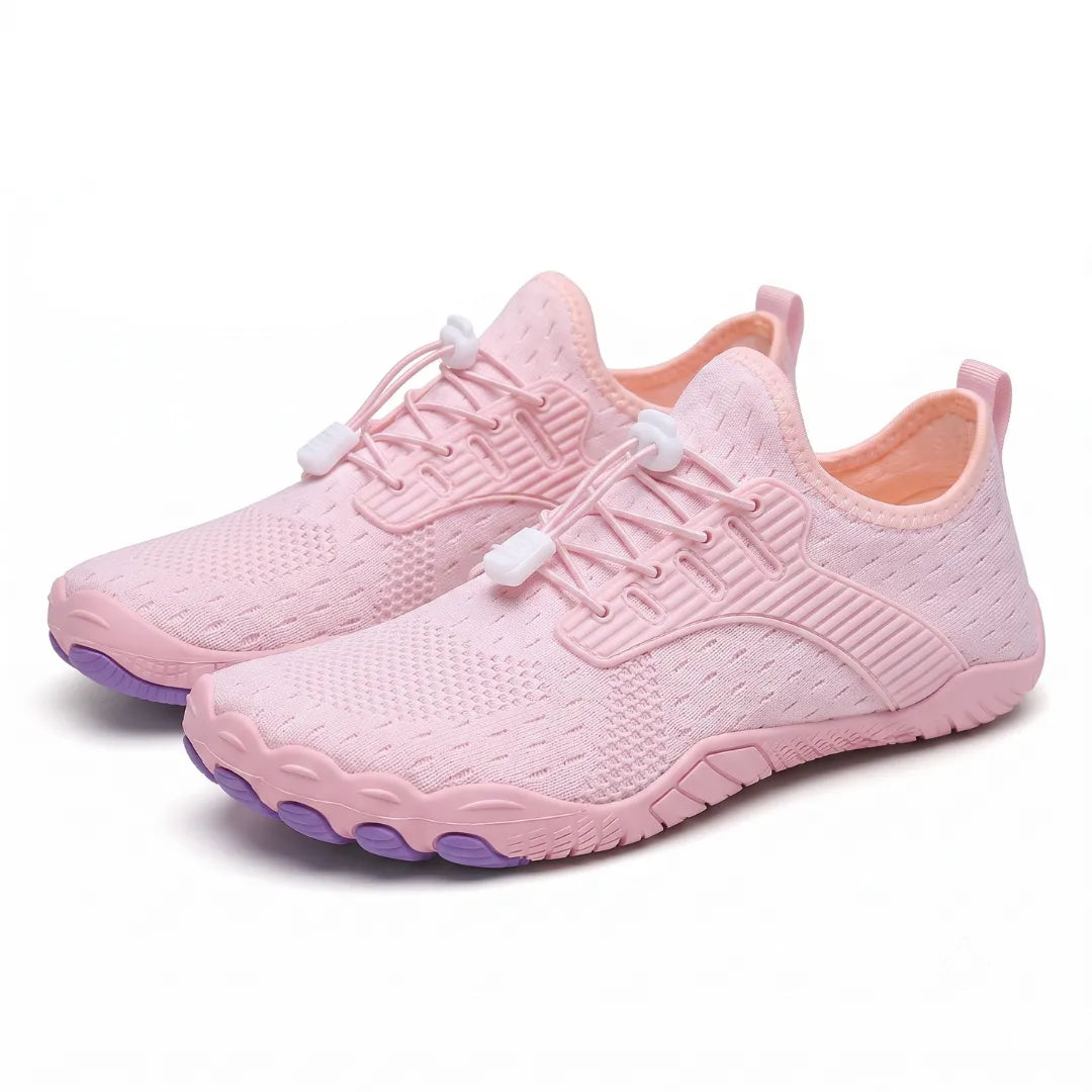 Pair of pink knit barefoot trainers seen from the front corner, with white toggle laces and purple toe-shaped sole pads. 34