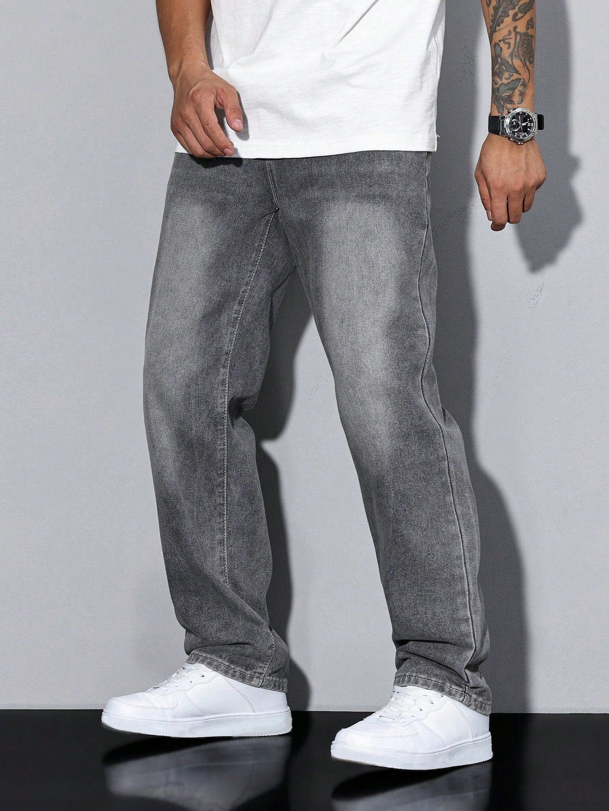 Front view of washed grey wide-leg jeans on a model standing with arms relaxed, white tee and trainers. 5