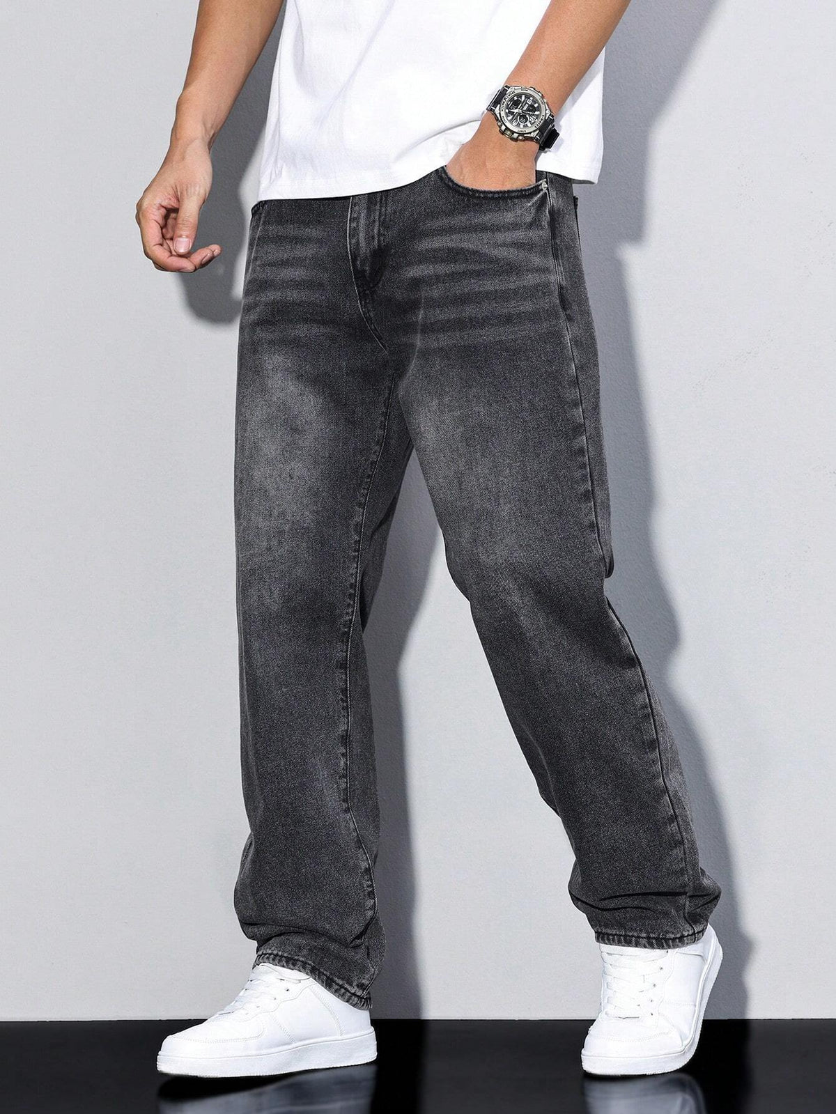 Faded charcoal-black loose jeans worn by a model with hand in pocket, showing whiskering at the hip. 7