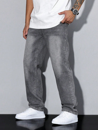 Side view of washed grey loose-fit denim jeans worn by a model with a white tee and white trainers, hand in pocket. 1