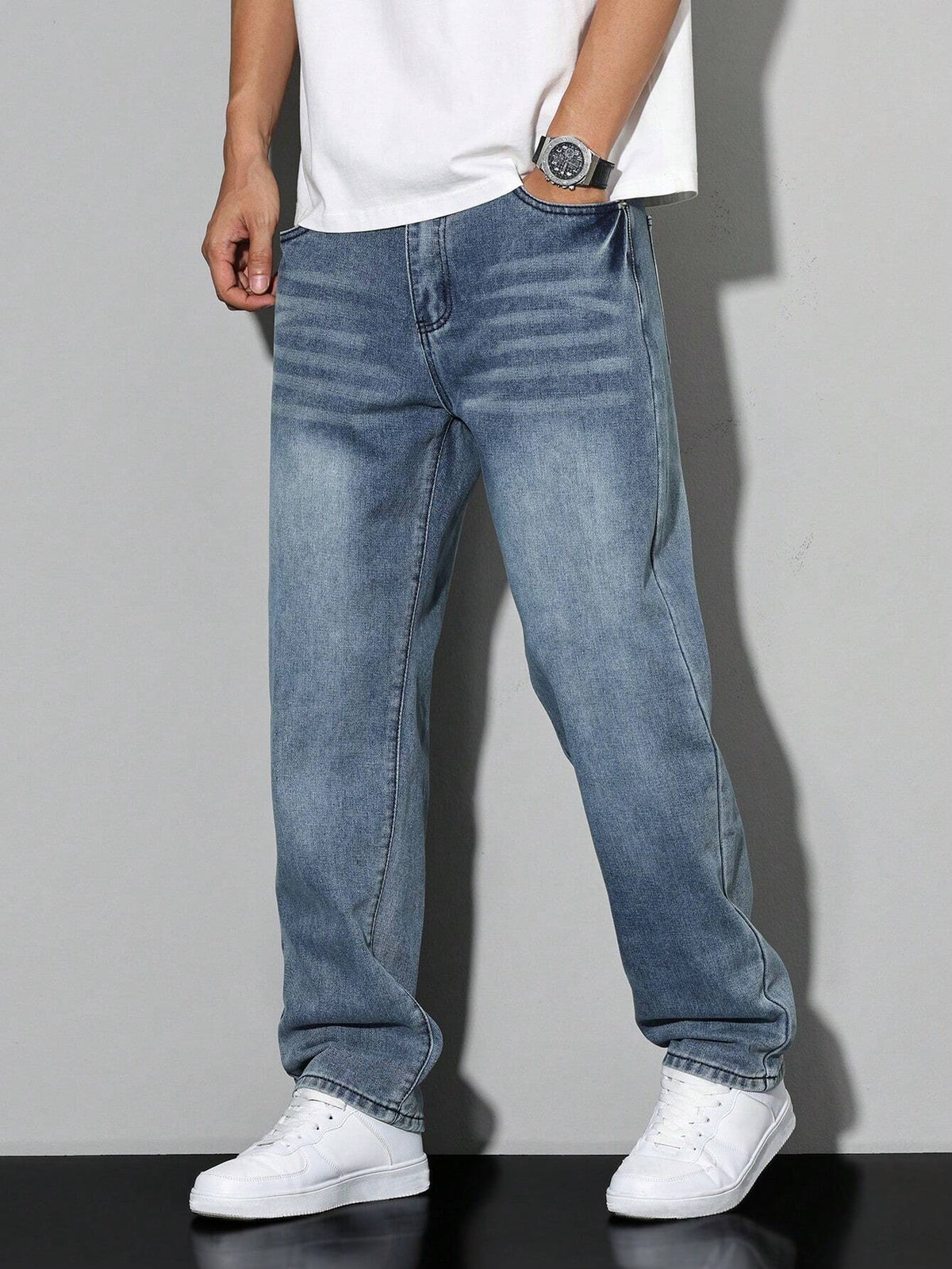 Faded steel-blue wide-fit jeans with whiskering at the hips, worn by a model in a white t-shirt and white trainers. 11