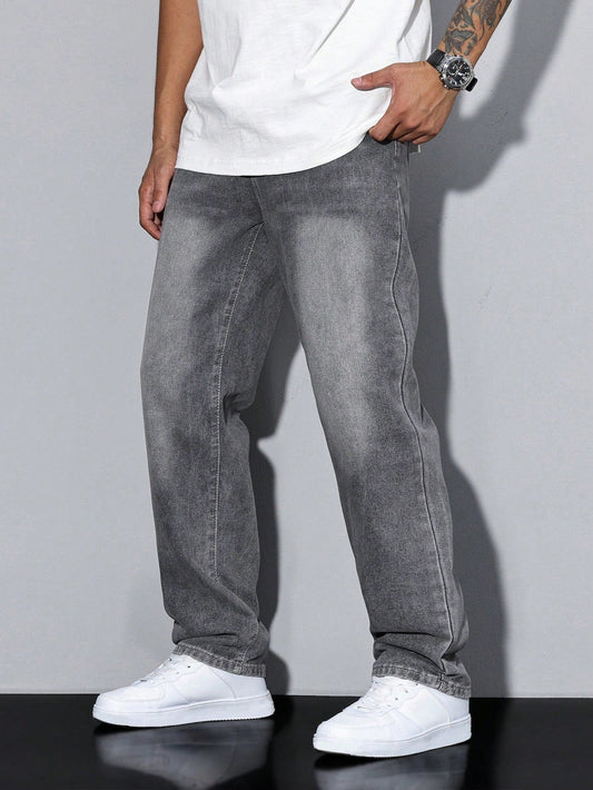 Side view of a man wearing grey washed wide-leg denim jeans with a white t-shirt and white trainers, one hand in pocket. 1