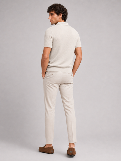 Back view of model in off-white knit polo with beige trousers and brown driving loafers 19