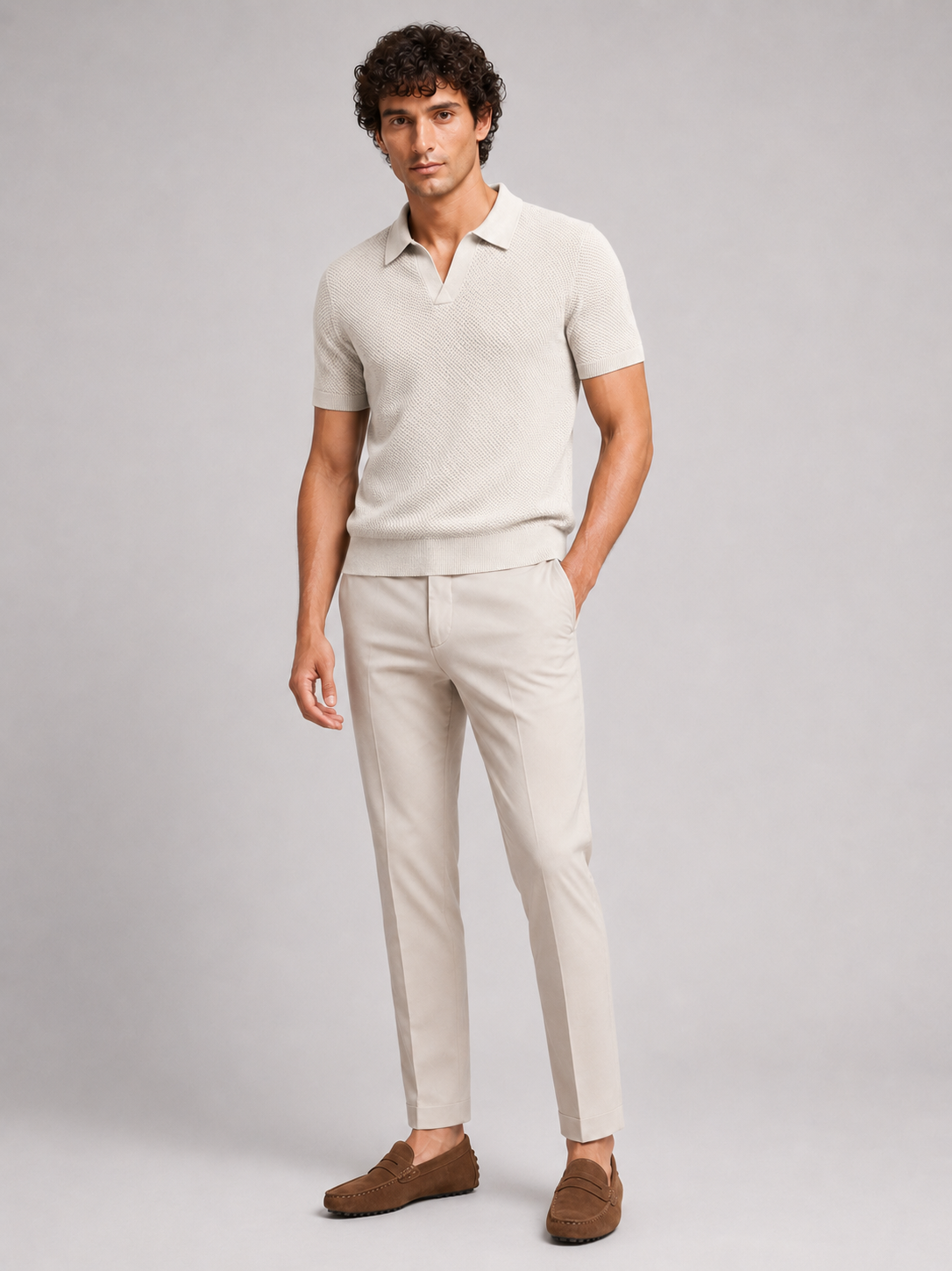 Full-length front view of model in off-white knit polo, beige trousers and brown suede loafers 18