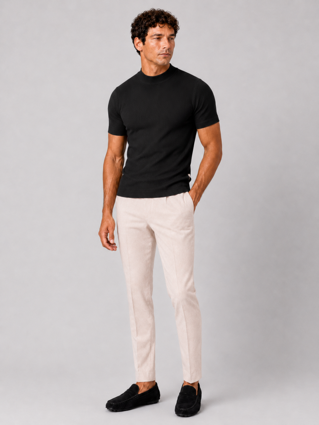 Full-length studio shot of the black ribbed top with cream trousers and black suede loafers. 18