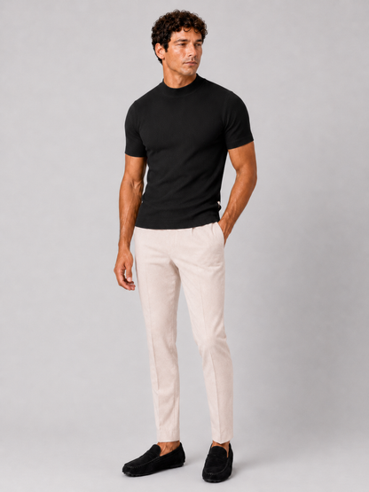 Full-length studio shot of the black ribbed top with cream trousers and black suede loafers. 18