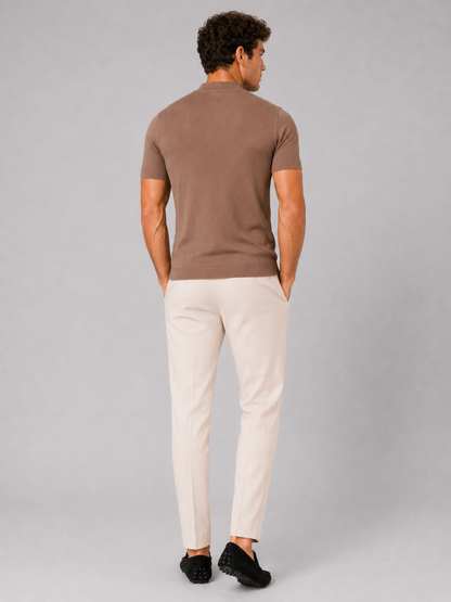 Back view of the brown ribbed top worn with cream trousers and black loafers, model's hands in pockets. 4