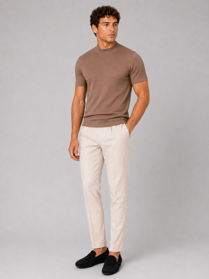 Full-length studio shot of the brown top worn with cream trousers and black suede loafers, model looking to the side. 3