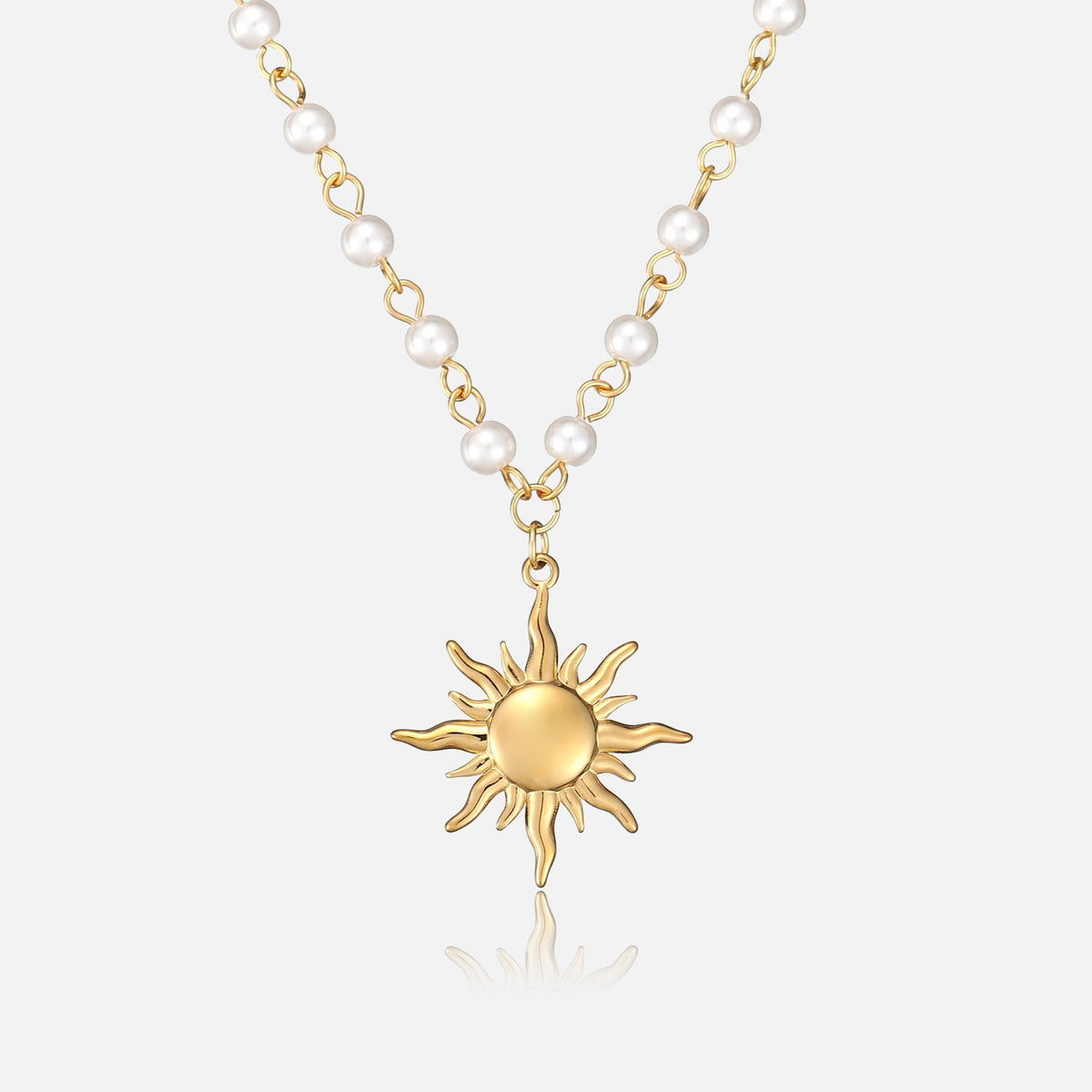 Front view of a gold sun pendant hanging from a chain of white pearls 1