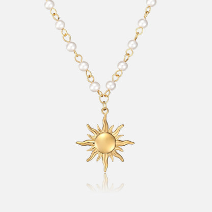 Front view of a gold sun pendant hanging from a chain of white pearls 1