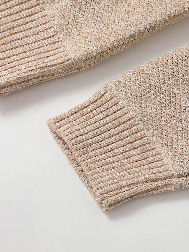 Close-up of the ribbed cuffs of the beige knit cardigan, with the textured knit of the sleeves above them. 6