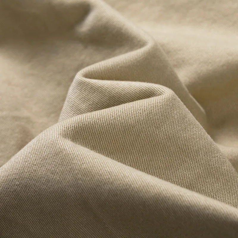 Close-up of soft folds of khaki twill fabric showing the fine diagonal weave. 8