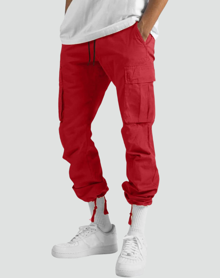 Red cargo trousers worn with the hem drawcords tightened into a jogger style, showing the side pocket, with white socks and trainers. 11