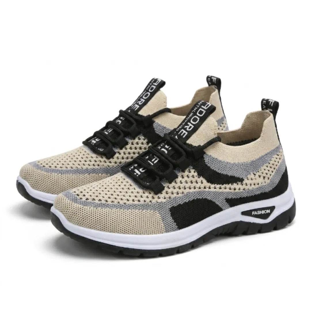 Pair of beige trainers with grey and black accents, perforated mesh uppers, black laces with lettered tabs and a white and black sole, angled view. 43