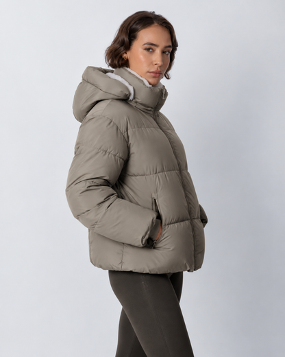 Side view of a taupe-grey puffer jacket with the hood up, showing the zipped hand pocket and cuff 19