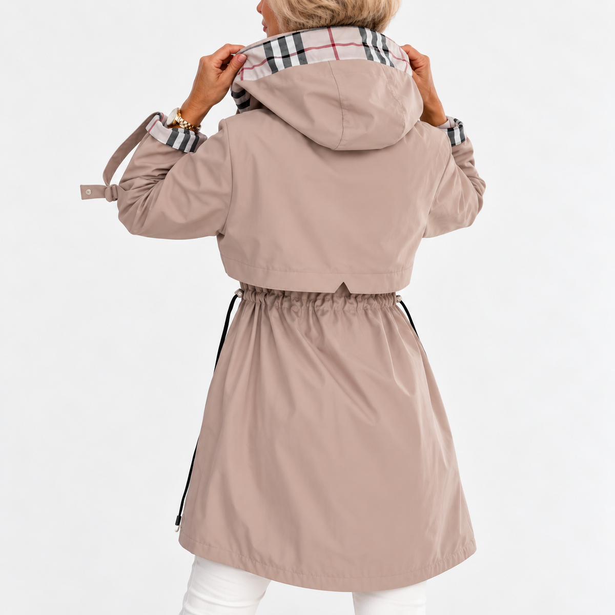 Back view of the beige coat on a model holding the hood, showing gathered drawstring waist and check lining 3
