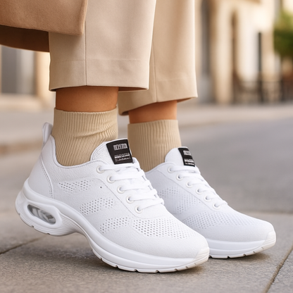 White perforated trainers with white air-cushion soles, worn with ribbed beige socks and wide beige trousers on a pavement. 8
