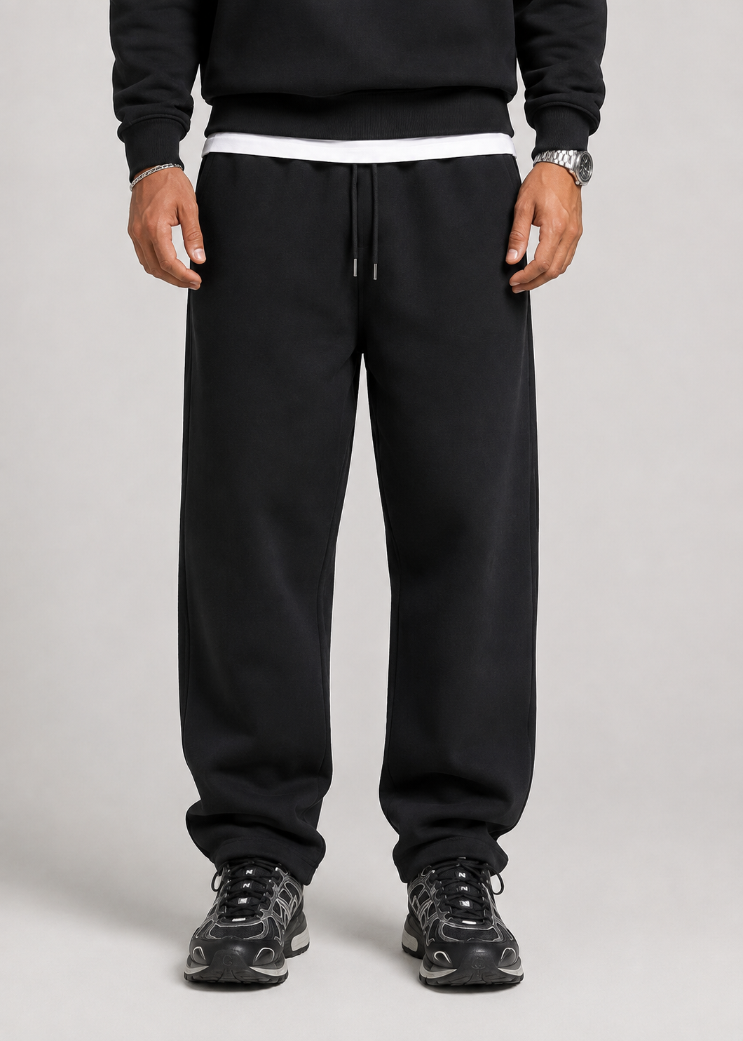 Front view of the black joggers from the waist down, showing the drawstring waistband, straight legs and black trainers. 6