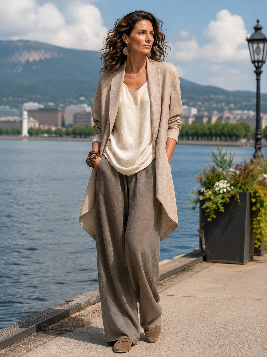 Model wearing the full three-piece set outdoors on a lakeside promenade, with hands in the trouser pockets and hills behind. 7