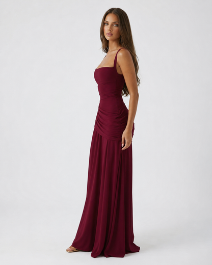 Side view of the burgundy maxi dress, with ruched hip detail and a long flowing skirt. 10