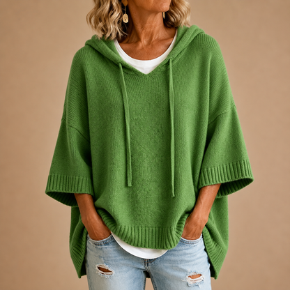 Green version of the knitted hooded poncho with wide ribbed cuffs, worn with a white top and ripped jeans. 5