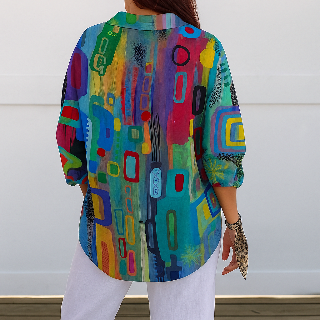 Back view of a model wearing the blouse, showing the continuous multicoloured abstract print across the back and sleeves, with a curved hem. 7