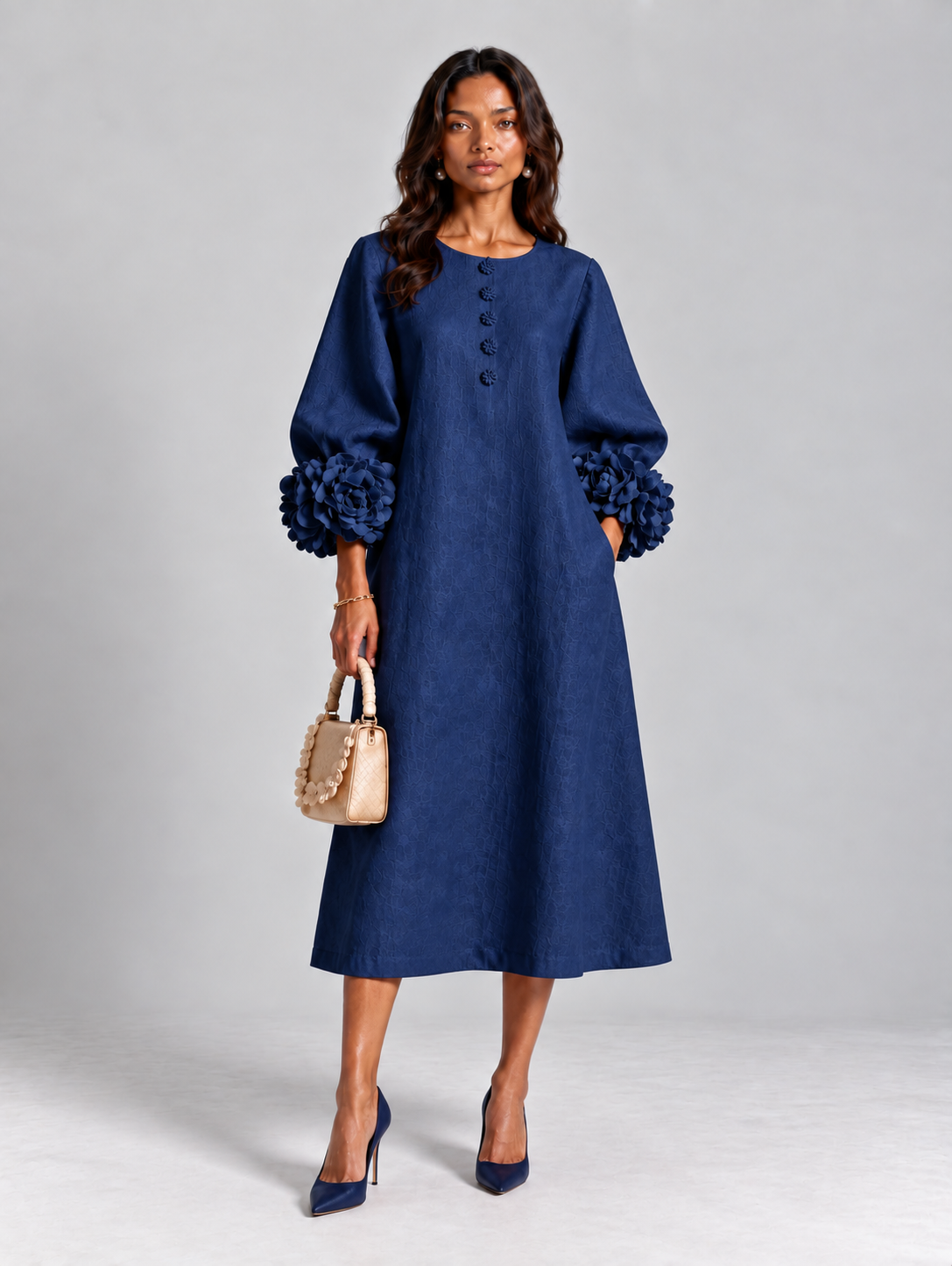 Model wearing the deep navy blue version of the dress with navy heels, holding a small beige petal-trimmed handbag. 10