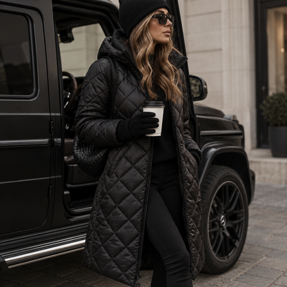 Model in the black quilted hooded coat, zipped and knee-length, with beanie, sunglasses and woven bag, leaning against a black off-road vehicle. 3