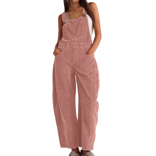 Model wears the ribbed corduroy dungarees in dusty pink, hands in the front pockets, with a bib pocket and wide, barrel-shaped legs. 1