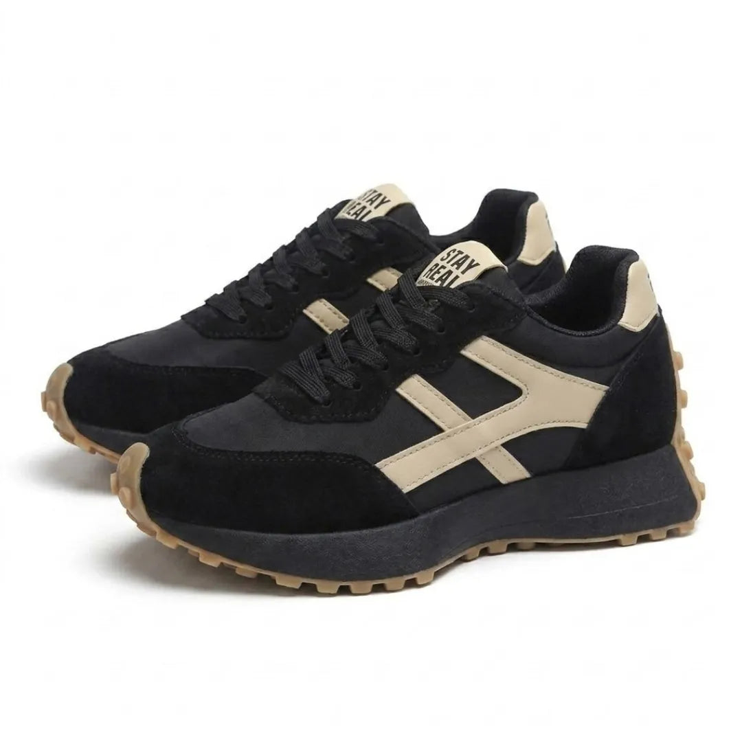 Pair of black trainers with cream stripes and gum soles, shown at an angle 18