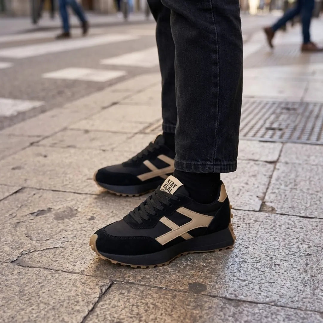 Black and cream trainers worn with dark jeans and black socks on a pavement 17